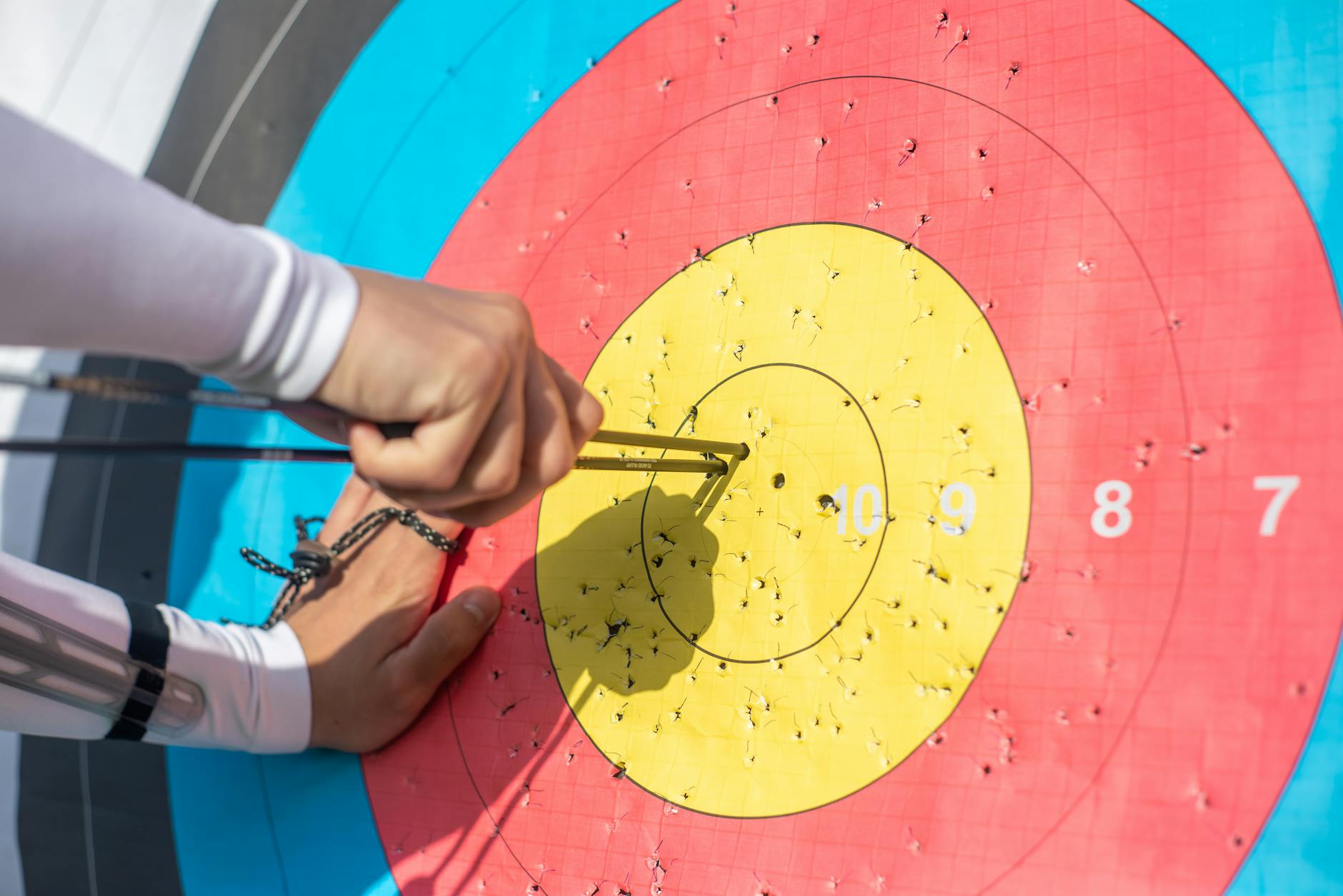 a person pulling arrows from archery target board